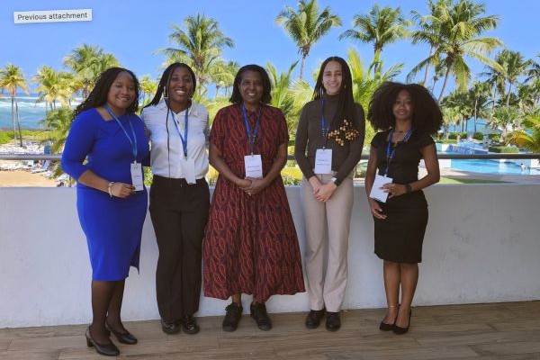 A group of women is posing for a photo outdoors, standing together and smiling.