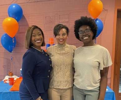 students and faculty standing next to orange and blue balloons