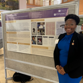 A woman standing in front of a poster, smiling in an indoor setting